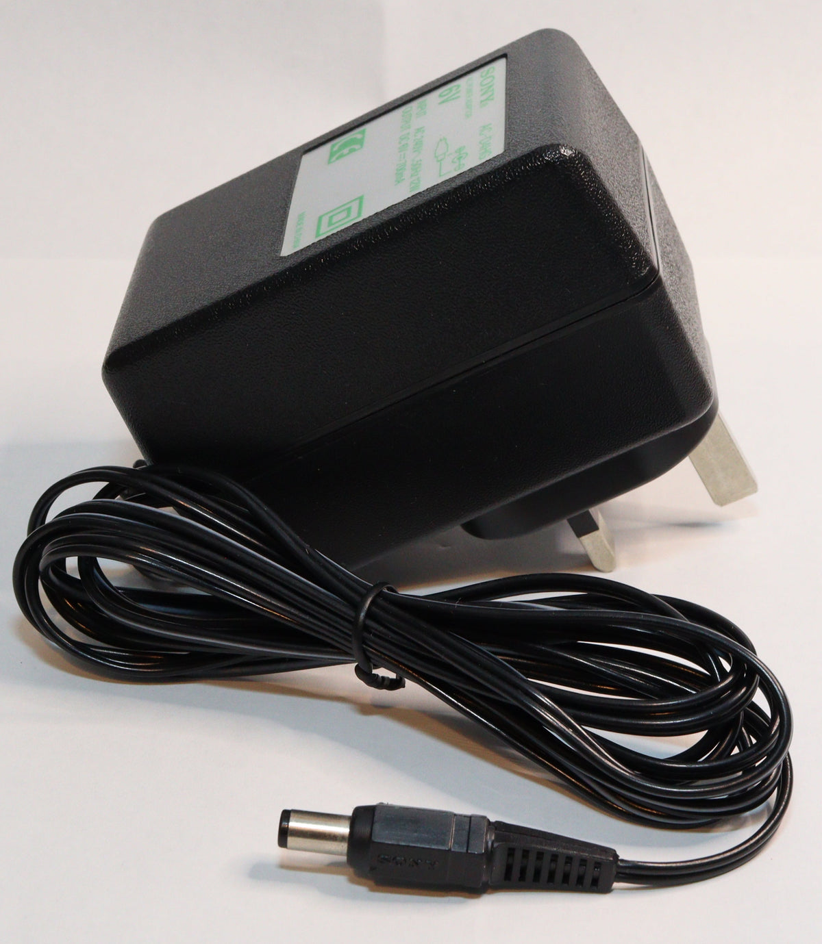 A black wall power adapter with a coiled black power cord and a barrel plug, photographed on a plain white background.