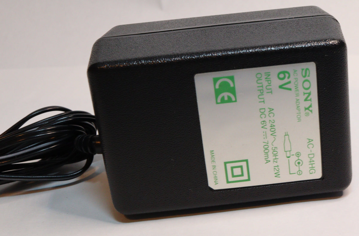 A black Sony 6V DC power adapter with a coiled black cable, featuring a white label with green text and certification logos, set against a plain white background.