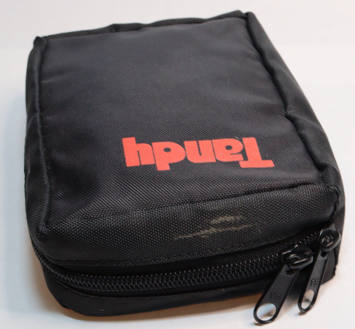 A black zippered fabric pouch with the brand name 'Tandy' printed in red on the front, photographed on a plain white surface.
